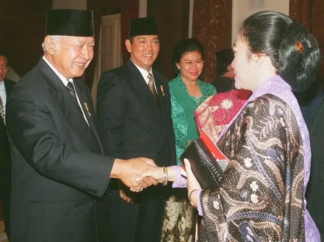 (Dokumentasi) Presiden Indonesia Soeharto (kiri) bersalaman dengan pemimpin oposisi yang sedang menghadapi tekanan politik, Megawati Soekarnoputri, usai upacara pengibaran bendera di Istana Kepresidenan dalam rangkaian perayaan Hari Kemerdekaan pada 17 Agustus 1996. Megawati menghadiri upacara tersebut dalam kapasitasnya sebagai putri Presiden pertama sekaligus pendiri bangsa Indonesia, Soekarno. Di tengah tampak Wakil Presiden Indonesia Try Sutrisno beserta istrinya, Tuti.