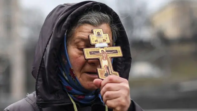 தலைநகரில் உள்ள சுதந்திர சதுக்கத்தில் ஒரு பெண் சிலுவையை ஏந்தி பிரார்த்திக்கிறார்