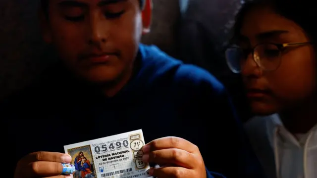 Sus dos hijos mostrando a los medios el boleto premiado que lleva el número 05490