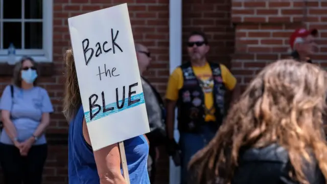 A woman holds a 'Back the Blue' placard during a pro-police rally.