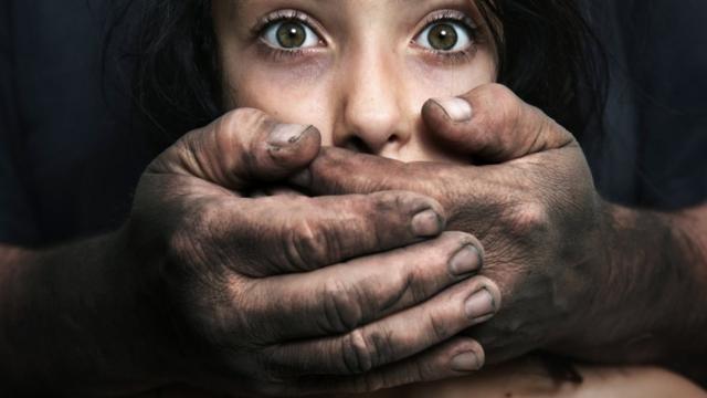 Foto ilustrativa sobre abuso infantil - homem segura com as duas mãos rosto de menina