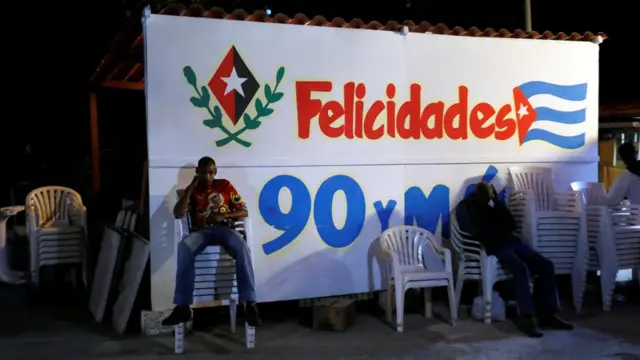 Cubanos frente a una valla celebrando los 90 años de Fidel Castro