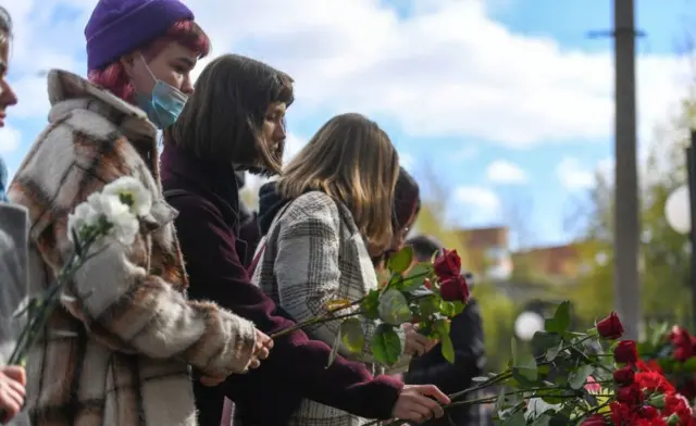 Students lay flowers at a makeshift memorial outside the university campus in Perm on September 21, 2021