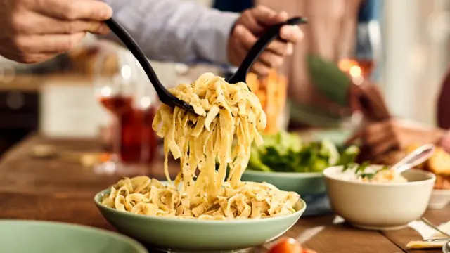 Um homem servindo macarrão