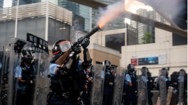 полиция применяет слезоточивый газ во врем протестов в Гонконге