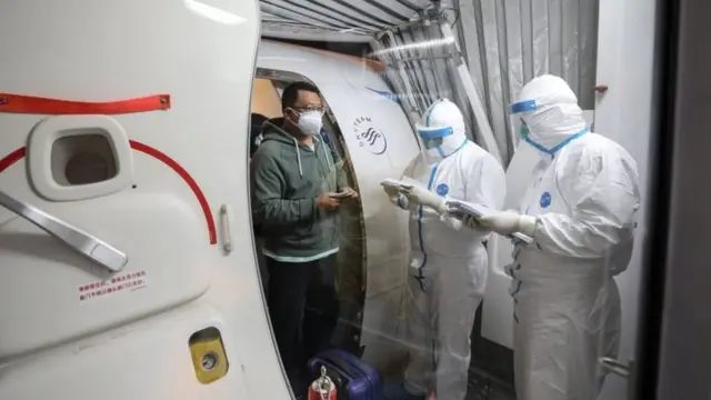 January 31, 2020 shows a man (L) disembarking from a Xiamen Airlines plane after arriving from the Thai capital Bangkok at Tianhe airport in Wuhan in China"s central Hubei province