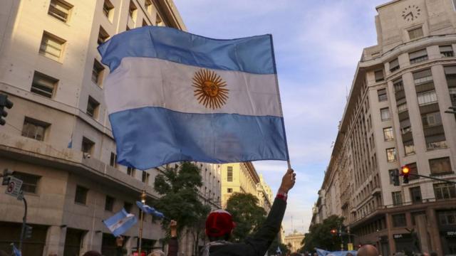 Hombre sostiene una bandera de Argentina.