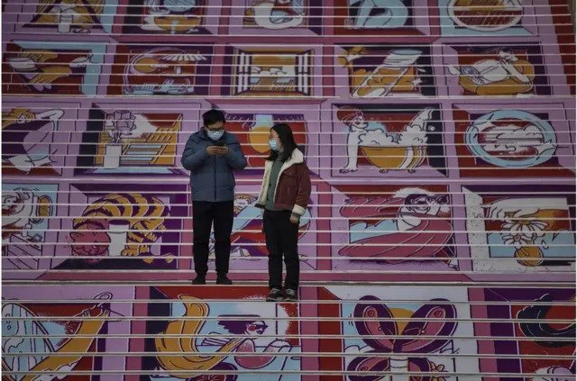 2021年1月10日，一男一女站在中国上海的一家购物中心外面。