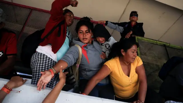 Mujer ayudando a otro a saltar la valla.