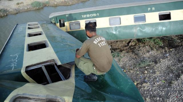 巴基斯坦信德省纳瓦布沙阿客运火车出轨事故现场救援人员在扭曲的车厢残骸中攀爬（6/8/2023）