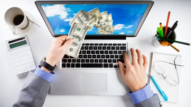 computadora con dinero volando.
