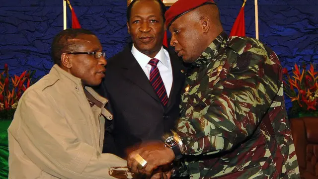 Le chef de la junte guinéenne, le capitaine Moussa Dadis Camara (à gauche), et le chef intérimaire de la junte guinéenne, le général Sekouba Konate (à droite), se serrent la main sous le regard du président du Burkina Faso, Blaise Campaore, le 15 janvier 2010 à Ouagadougou, lors d'une réunion