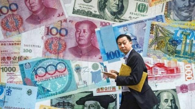 Человек на фоне рисунков китайской валюты