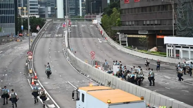 Police officers dissolve the barricades placed by demonstrators in Hong Kong on June 13, 2019