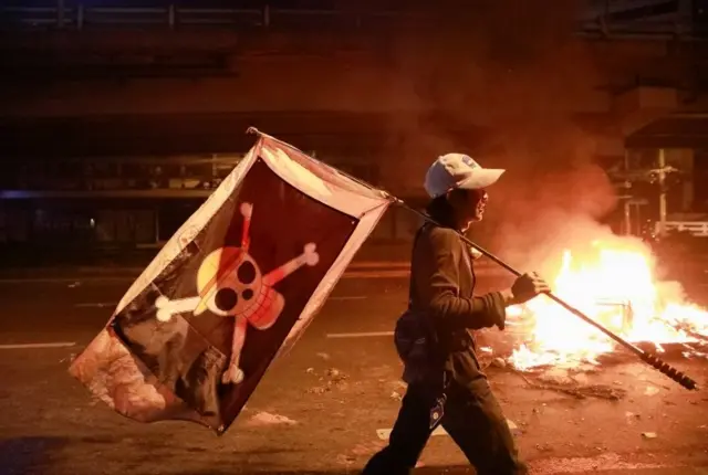 คนถือธงหัวกะโหลก เดินผ่านกองไฟ