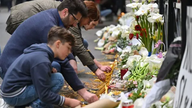 Люди несут цветы и зажигают свечи у места трагедии