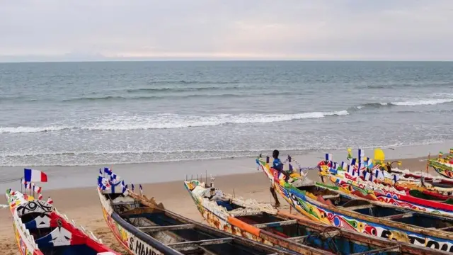 Plage avec une large vue sur l'océan Atlantique avec des bateaux en bois au premier plan.