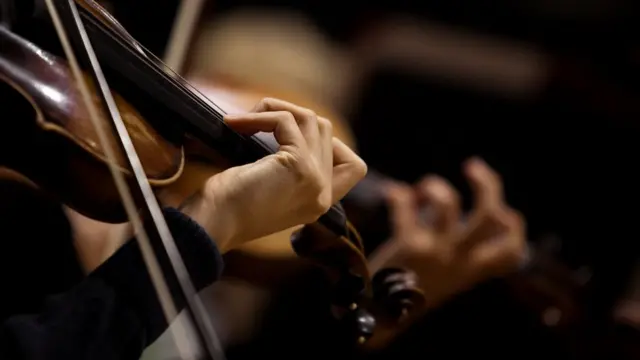 ภาพระยะใกล้ของมือที่กำลังสีไวโอลิน