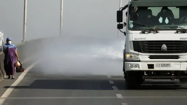 женщина, идущая по шоссе, по струей из грузовика