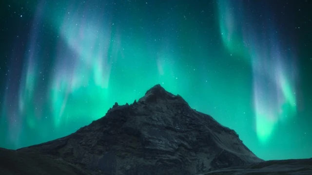 The Northern Lights at the top of the Skogafoss waterfall in Iceland.