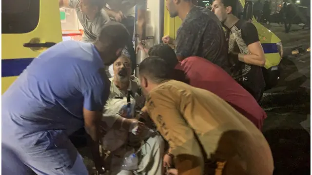 أشخاص ينقلون مصابا إلى سيارة إسعاف