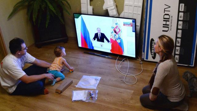 Молодая семья смотрит послание Владимира Путина Федеральному собранию