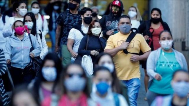 Pessoas andando com máscaras na rua