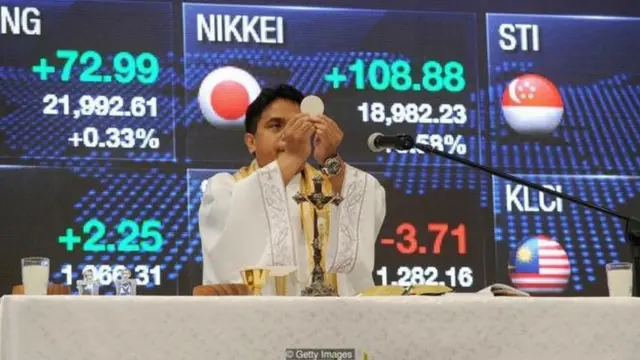 A Roman Catholic priest officiates mass on the first day of trading at the Philippine Stock Exchange in Manila