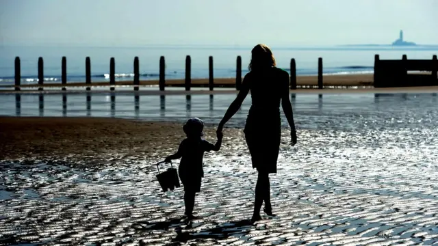 Woman and child walking on the beach at Blyth