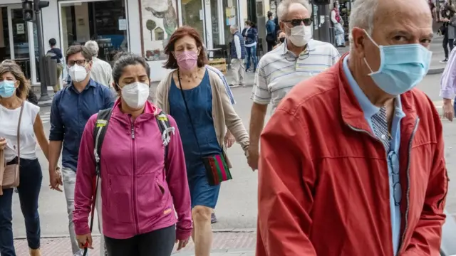 Pessoas com máscara andam na rua