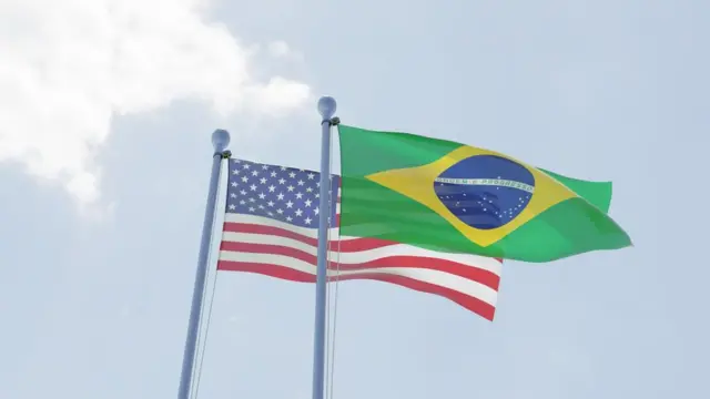 Bandeiras dos EUA e do Brasil sob o céu