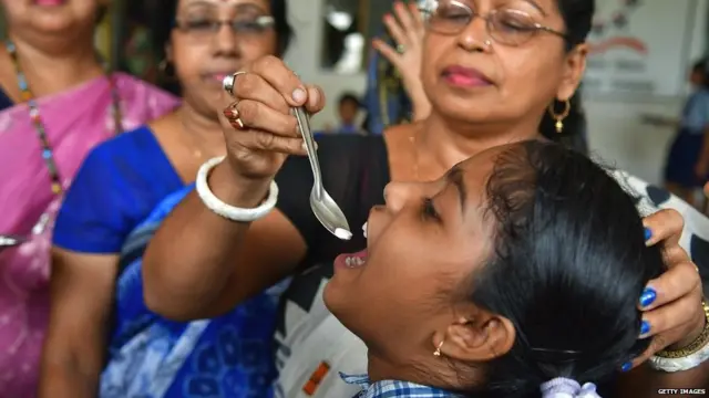 A health worker is seen deworming a kid