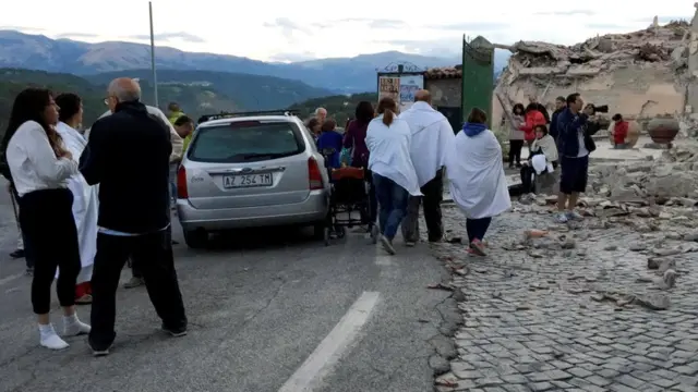 People stand along a road following a quake in Amatrice