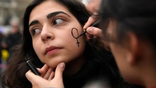 स्पेन के बार्सिलोना में चेहरे पर टैटू बनवाती एक युवती