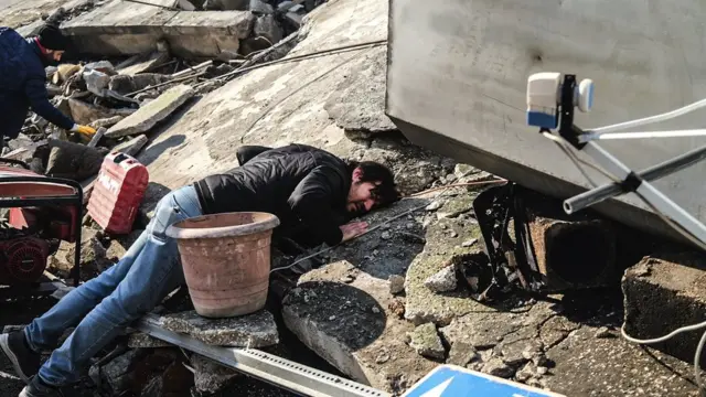 A man puts his ear to the rubble trying to hear trapped people in the Hatay province of Turkey. 