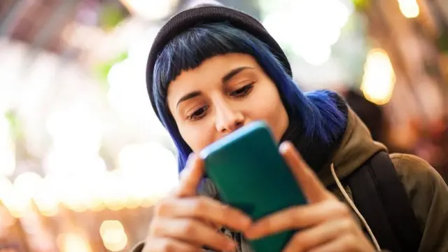 Una joven escribiendo en su teléfono