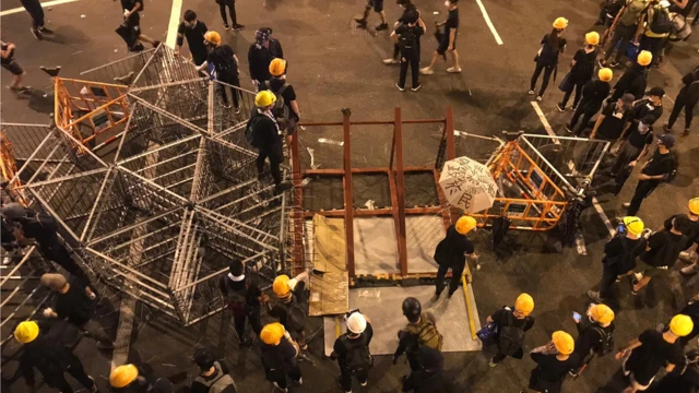 示威者集結做路障，从远处运来更多的铁栏。