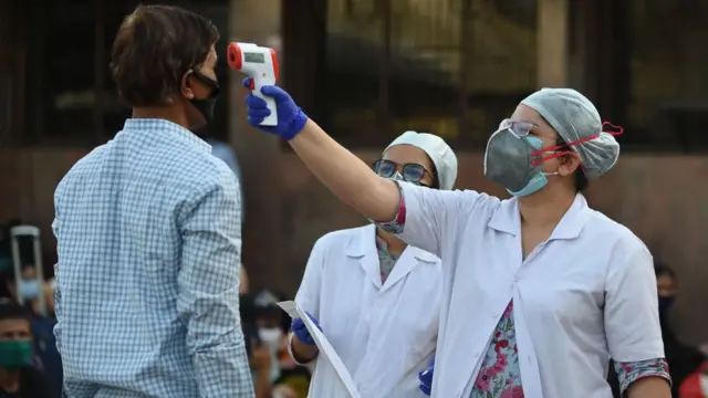 તાપમાન માપતા સ્વાસ્થ્યકર્મી