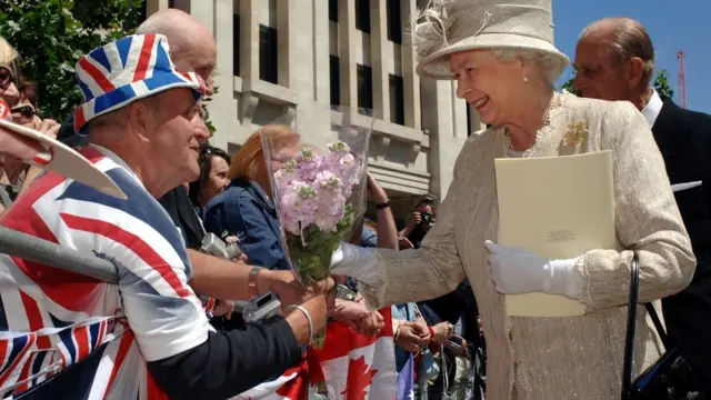 Queen Elizabeth II accepts flowers from Royal fan Terry Hutt outside at St Paul's Cathedral, London, after a service of thanksgiving in honour of her 80th birthday
