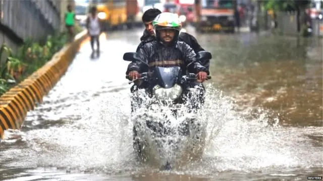 रस्त्यावर साचलेल्या पाण्यातून वाट काढणारा दुचाकीस्वार