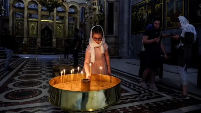 Une jeune fille place une bougie dans l'église du Saint-Sépulcre, dans la vieille ville de Jérusalem (11 avril 2022).