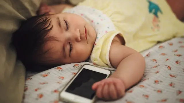 نوزادی در کنار آی فن خوابیده است