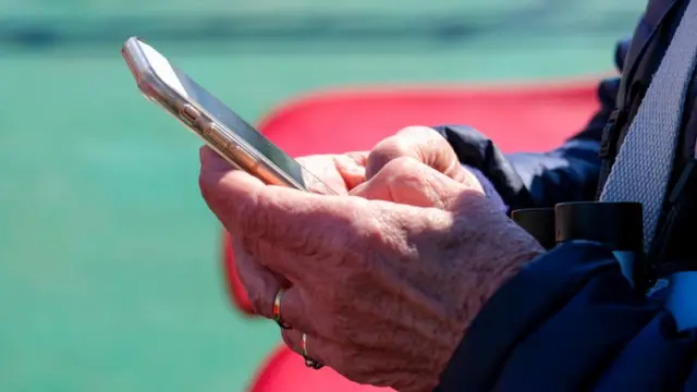 Una persona adulta escribe en un teléfono.