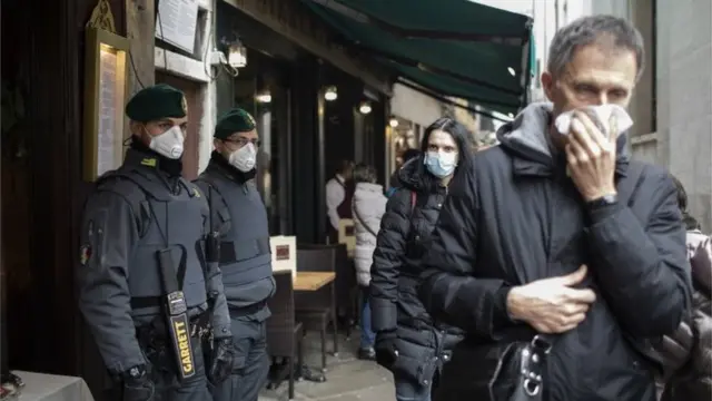 Police and members of the public wear protective face masks during the Carnival in Venice, Italy, 23 February 2020.
