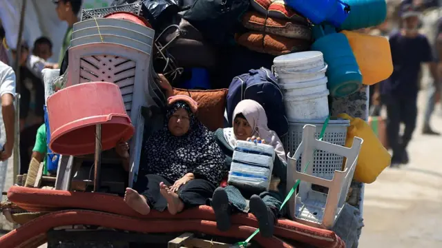Mujeres palestinas desplazadas huyen del norte de Gaza en un carro lleno de sus pertenencias, en la ciudad de Gaza (21 de agosto de 2025).