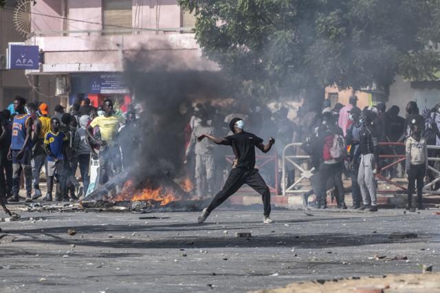 Un jeune manifestant sénégalais lançant des pierres aux forces de l'orde