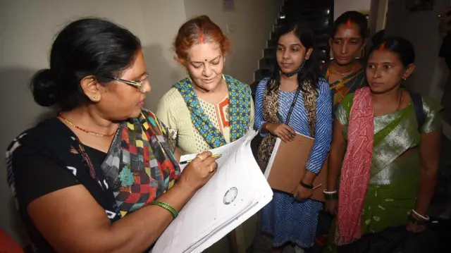 একজন গণনাকারী বাড়ি বাড়ি গিয়ে তথ্য যাচাই করছেন।