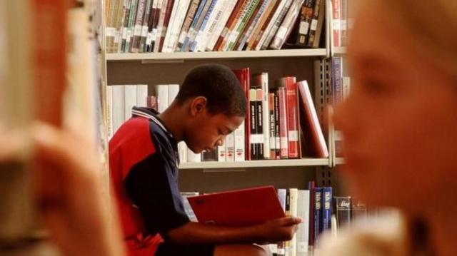 Jovem negro lendo um livro em uma biblioteca