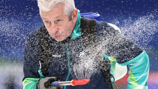 Чоловік роздмухує сніг на Олімпіаді