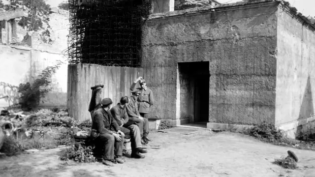 Na czarno-białym zdjęciu widać żołnierzy strzegących w 1946 roku Führerbunkra, w którym Adolf Hitler i Eva Braun popełnili samobójstwo.